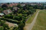 16: Sailors are out on the sea in the distance as we pan back to the pretty gardens of properties adjacent to Southwold Common.